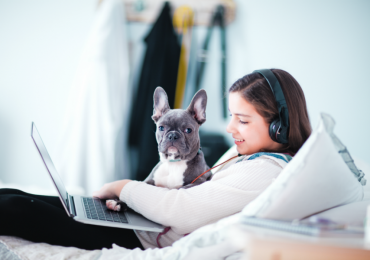 Cuarentena niña viendo computadora y audífonos con un perro