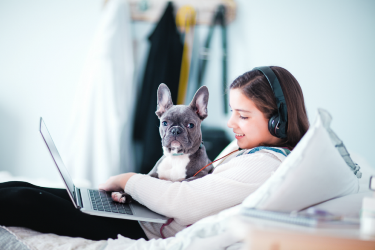 Cuarentena niña viendo computadora y audífonos con un perro